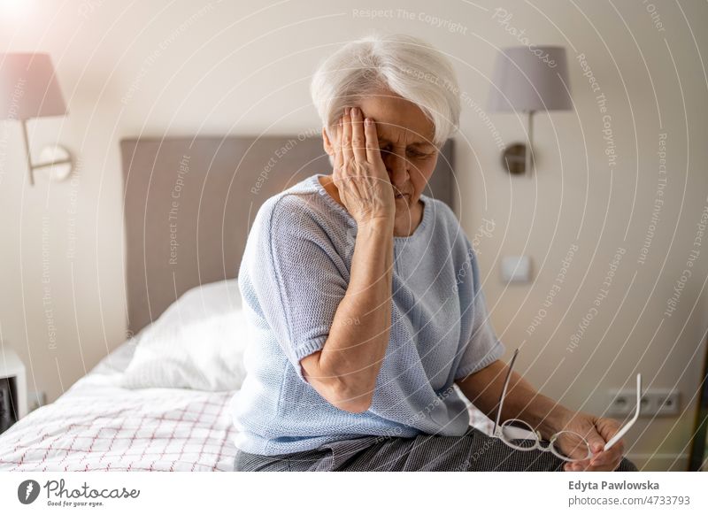 Ältere Frau leidet unter Kopfschmerzen allein zu Hause häusliches Leben älter Oma Großmutter graue Haare heimwärts im Innenbereich Lifestyle reif alt