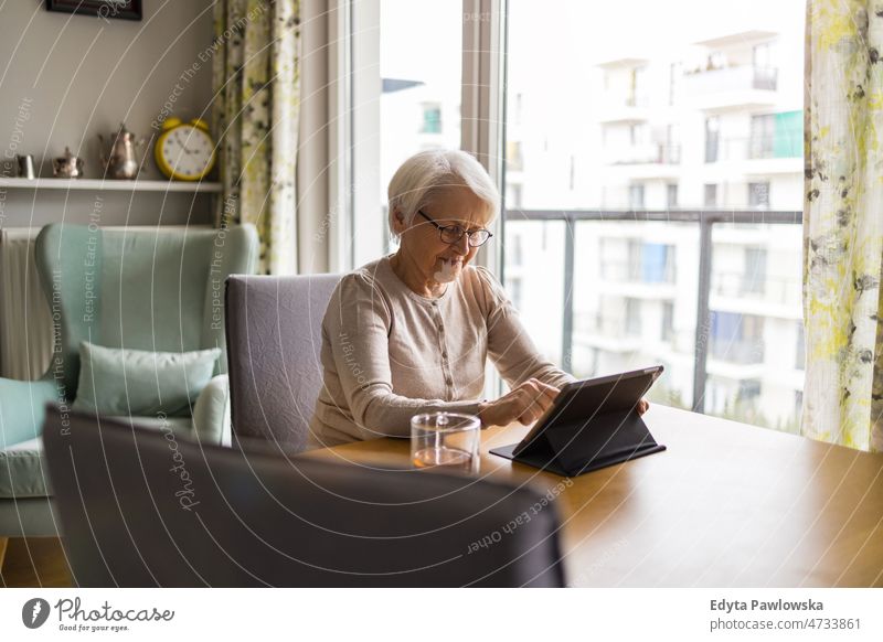 Ältere Frau benutzt ein digitales Tablet zu Hause Tablette digitales Tablett online Internet modern Technik & Technologie Mitteilung Anschluss Wohnzimmer Brille
