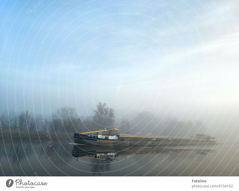Morgens am Mittellandkanal taucht aus dem Nebel auf der spiegelglatten Wasseroberfläche ein Schiff auf. Schifffahrt Wasserfahrzeug Außenaufnahme Farbfoto blau