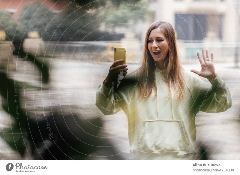 Hübsche kaukasische Frau mit Smartphone hat gute Zeit im Freien. Porträt der trendigen Millennial Mädchen mit blonden Haaren trägt modische Kleidung Handy