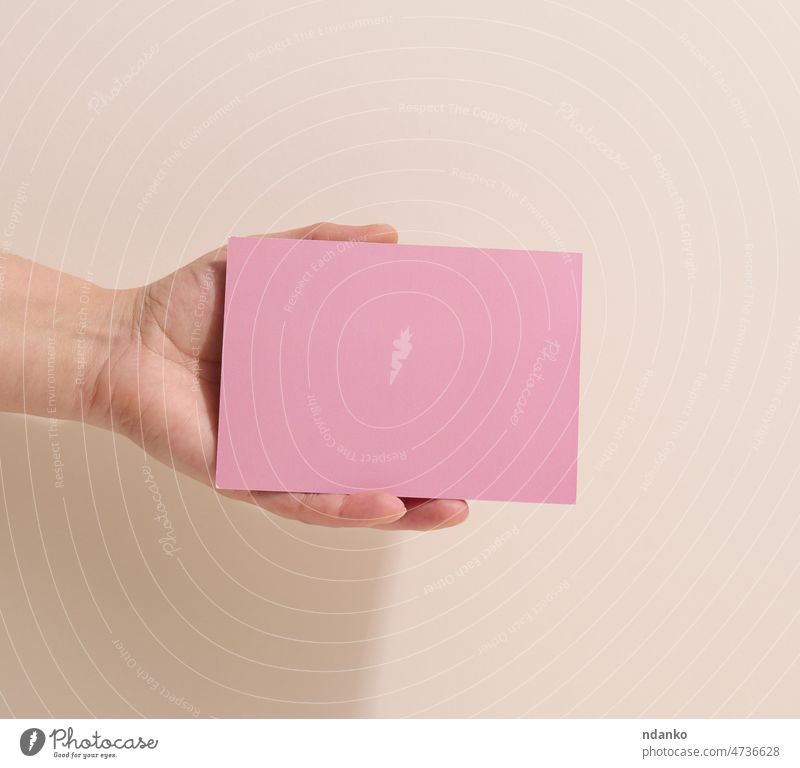 Weibliche Hand hält leeres rosa Papier auf einem beigen Hintergrund. Bild oder Text kopieren und einfügen, Nahaufnahme Anzeige Erwachsener inserieren Inserat
