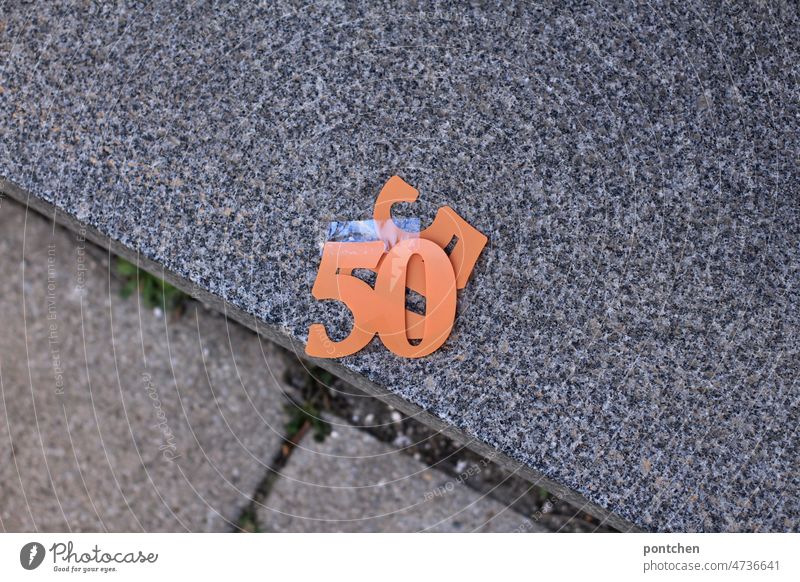 Eine 50 fünfzig in orange liegt auf einem Gehsteig.  Plastikzahl, zahl, alter.  Geburtstag , runder Geburtstag, Feier, Dekoration, zahlen dekoration geburtstag