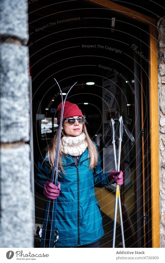 Frau mit Skiern verlässt Gebäude Skifahrer Mast Skigebiet warme Kleidung aktiv Gerät ruhen kleben Lifestyle Dame bereit vorbereiten Wochenende lässig Stil