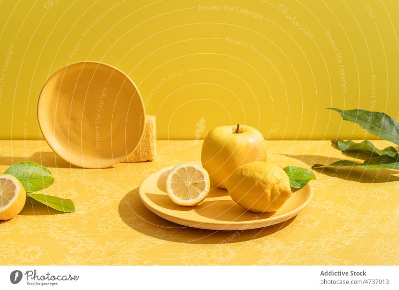 Helle Komposition aus Keramikteller mit Zitrone und Apfel Zitrusfrüchte Vitamin halbiert gelb Frucht reif Gesundheit Konzept Lebensmittel lebhaft lecker