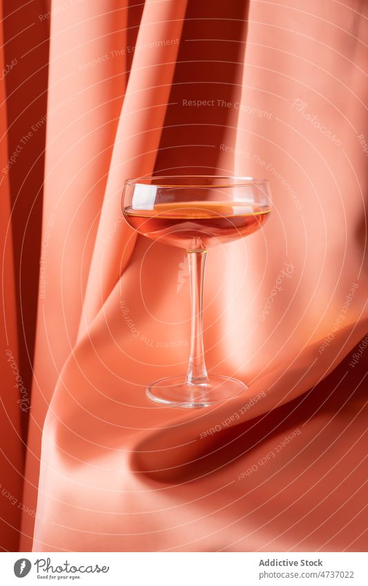 Glas mit alkoholischem Getränk auf rotem Stoff Alkohol Rosenwein trinken Champagne Vorhang Schnaps Kristalle Zusammensetzung elegant Glaswaren durchsichtig