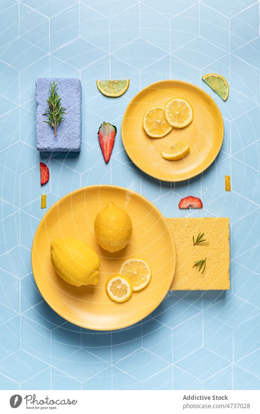 Helle Komposition aus exotischen Früchten und Erdbeeren auf Tellern flache Verlegung Zitrone Zitrusfrüchte frisch dienen Vitamin Rosmarin Zusammensetzung
