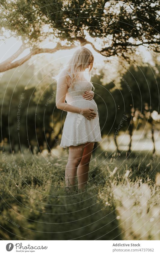 Positive schwangere Frau im grünen Wald stehend Schwangerschaft Sommer Park warten erwarten pränatal Glück Bauch mütterlich Dame filigran Kleid Mutterschaft