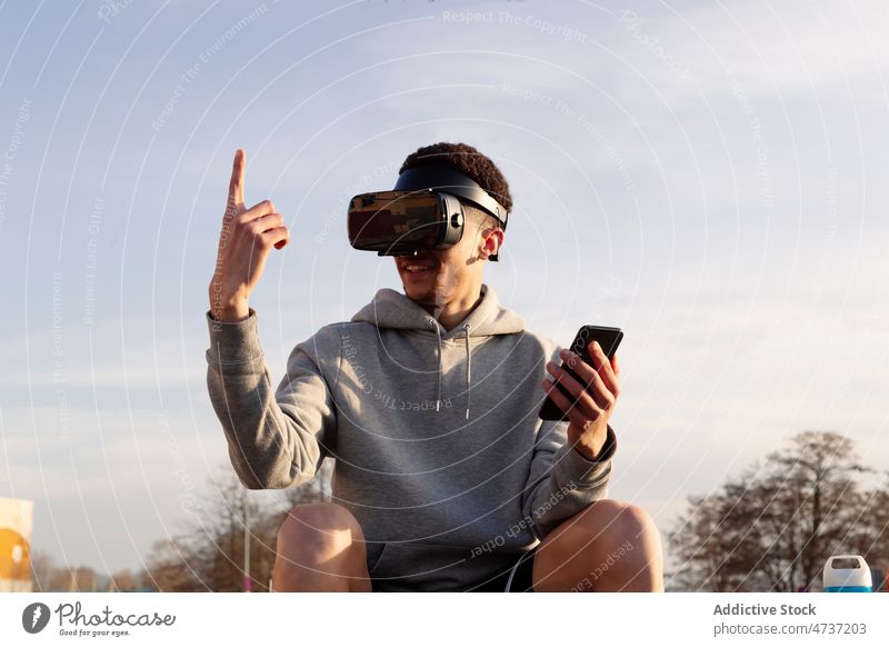 Mann mit VR-Headset und Smartphone in der Stadt Cyberspace simulieren erkunden Straße Browsen futuristisch Zeigefinger Virtuelle Realität digital männlich