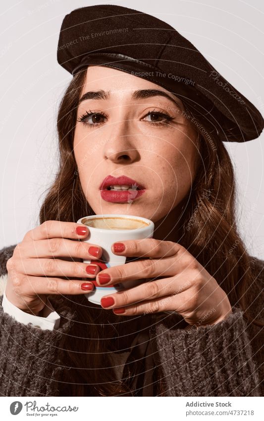 Stilvolle Dame mit einer Tasse Kaffee im Studio Frau Model Heißgetränk Getränk trinken Becher Porträt Baskenmütze warm Freizeit Persönlichkeit Pullover angenehm
