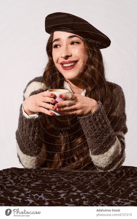 Stilvolle Dame mit einer Tasse Kaffee im Studio Frau Model Heißgetränk Getränk trinken Becher Porträt Baskenmütze warm Freizeit Persönlichkeit Pullover angenehm