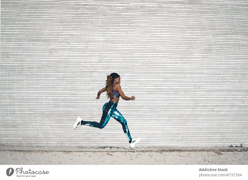 Aktive schwarze Frau, die während des Trainings auf der Strandpromenade läuft laufen Herz physisch passen Bewegung Fitness aktiv Rastalocken Laufsteg
