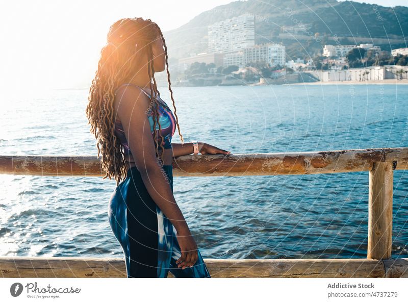 Schwarze Frau in Sportkleidung lehnt an einem Zaun an der Uferböschung Stauanlage passen MEER Training nachdenklich Wellness Gesundheit sportlich ernst