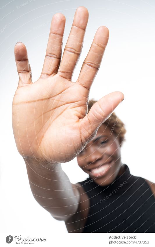 Glückliche schwarze Frau, die der Kamera eine "Hallo"-Geste zeigt gestikulieren Hi positiv Handfläche froh Gruß sich[Akk] melden zeigen Optimist manifestieren