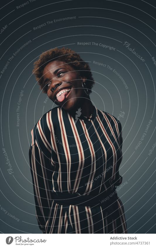 Lustige schwarze Frau zeigt Zunge im Studio lustig ausspannen Spaß haben Gesicht machen spielerisch Grimasse unanständig so tun, als ob sorgenfrei positiv