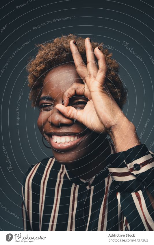 Lächelnde schwarze Frau zeigt OK-Geste im Studio gestikulieren Porträt Zeichen positiv Symbol kindisch gut spielerisch Glück expressiv heiter Optimist froh