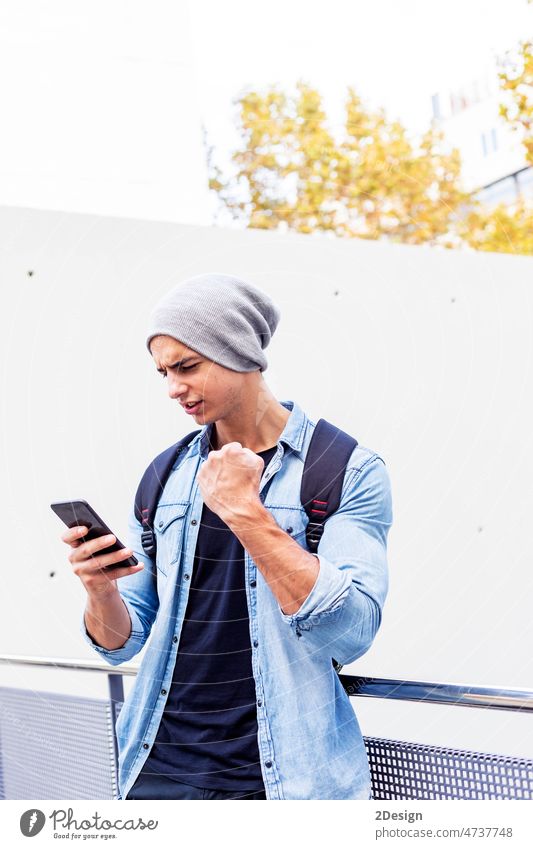 Außenporträt eines modernen jungen Mannes mit Mobiltelefon auf der Straße. 1 Erwachsener attraktiv Rucksack lässig Kaukasier charmant heiter Großstadt
