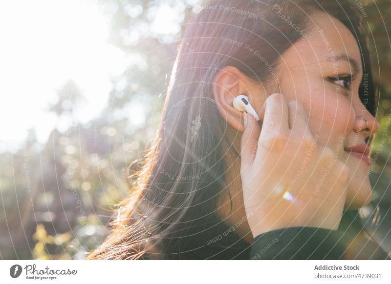 Ethnische Frau steckt sich kabellose Ohrstöpsel ins Ohr zuhören Drahtlos benutzend Musik Hobby Anschluss Wiedergabeliste angezogen Gesang Kopfhörer