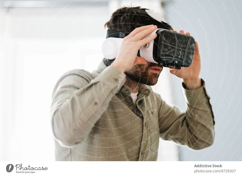 Ernster ethnischer Mann, der eine VR-Brille trägt und wegschaut erkunden Virtuelle Realität Konzentration Innovation Cyberspace ausrichten ernst simulieren