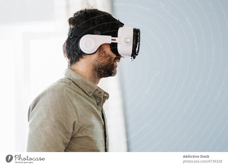 Ernster ethnischer Mann, der eine VR-Brille trägt und wegschaut erkunden Virtuelle Realität Konzentration Innovation Cyberspace ernst simulieren eintauchen