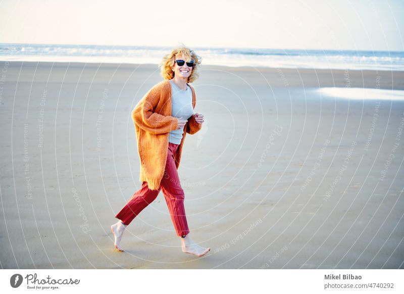 Junge reife blonde kaukasische Frau läuft im Freien in einem Strand in einem sonnigen Tag.  Lifestyle-Konzept. Porträt Wellness Frauen Gesundheit freudig rennen