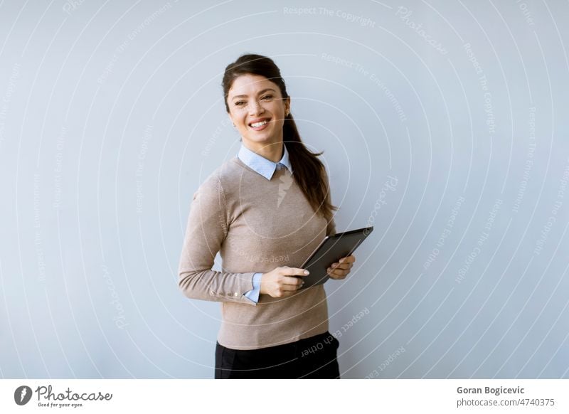 Junge Geschäftsfrau, die an einer weißen Bürowand steht und ein digitales Tablet benutzt Erwachsener attraktiv Business Karriere Kaukasier Überprüfung Single