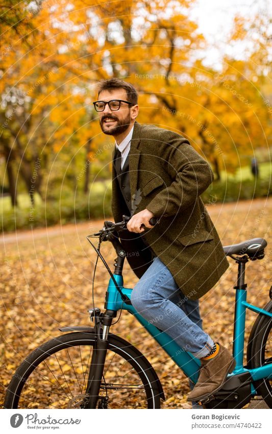Junger Mann mit Elektrofahrrad im herbstlichen Park Fahrrad jung Natur elektrisch Lifestyle im Freien Aktivität Farbe Zyklus Mitfahrgelegenheit Sommer Tag