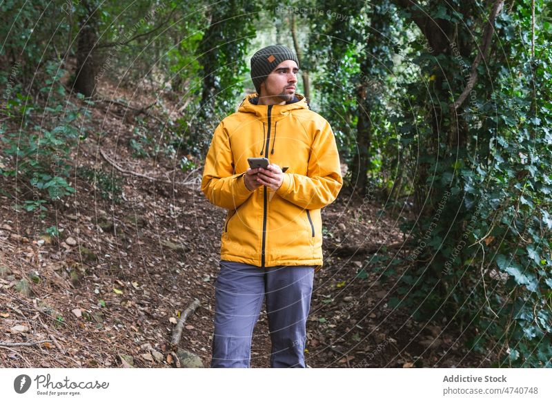 Mann surft mit Smartphone im Wald Wanderer Natur Trekking Reise Wanderung Browsen online Ausflug Wälder erkunden Aktivität Abenteuer Vollbart männlich Entdecker