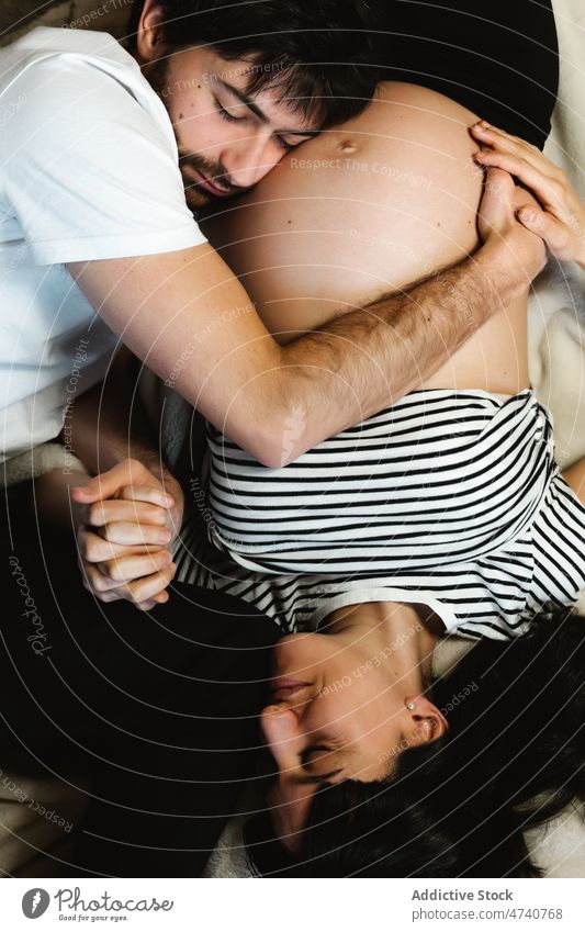 Zärtlicher Mann umarmt schwangere Frau auf dem Bett Paar Umarmen Umarmung Bauch Liebe Schwangerschaft Lügen Angebot Partnerschaft Zusammensein sanft
