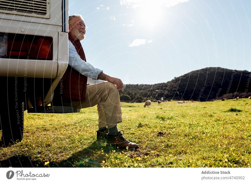Älterer Mann sitzt in der Nähe von Wohnmobilen in der Natur PKW rv Feld Autoreise reif Senior Reise Wohnwagen Anhänger Landschaft Verkehr geparkt männlich