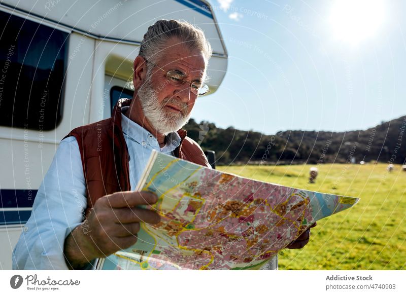 Älterer Mann mit Karte in der Nähe des Wohnwagens Wohnmobil PKW rv Natur Autoreise Senior Landkarte navigieren prüfen reif Reise Feld Anhänger Landschaft