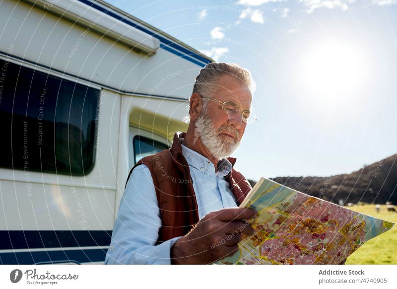Älterer Mann mit Karte in der Nähe des Wohnwagens Wohnmobil PKW rv Natur Autoreise Senior Landkarte navigieren prüfen reif Reise Feld Anhänger Landschaft