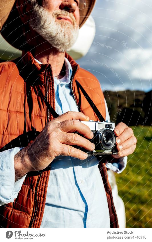 Anonymer Mann mit Fotokamera in der Natur Reisender Fotoapparat Fotograf Feld Ausflug Hobby Freizeit Vollbart grasbewachsen Gras Fotografie reisen ländlich