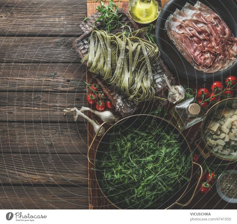 Italienisches Essen Hintergrund mit traditionellen Zutaten auf rustikalen Holztisch Küche Italienische Küche Spätzle Parmaschinken Rucola Tomaten Parmesankäse