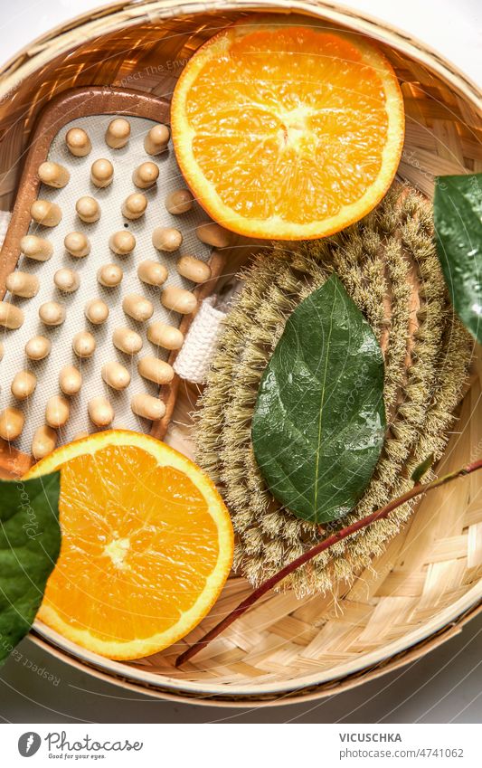 Nahaufnahme von Körperbürsten für Trockenbürsten zur Reduzierung von Cellulite mit grünen Blättern und Orange abschließen Cellulite reduzieren grüne Blätter