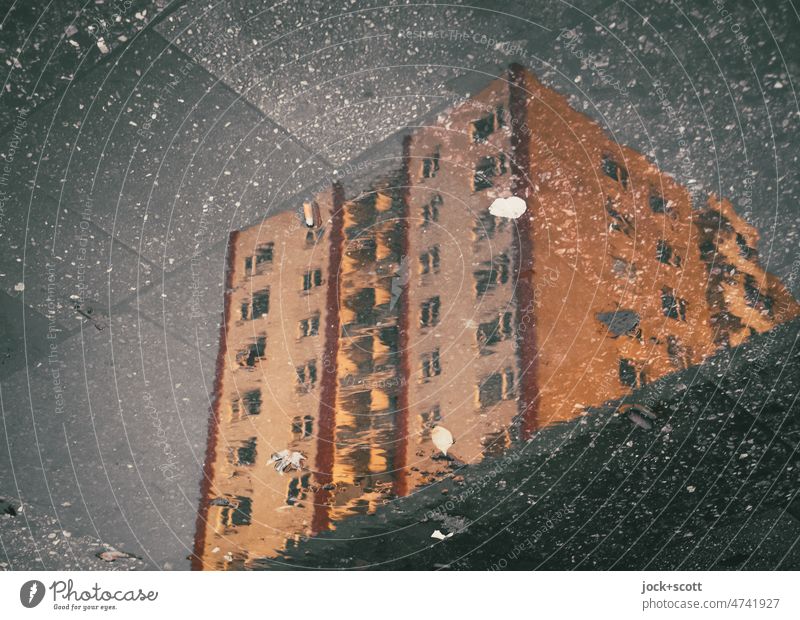 In der Pfütze spiegelt sich ein hohes Wohngebäude nach dem Regen Wohnhaus Reflexion & Spiegelung Bürgersteig Bodenplatten Fassade Hintergrund neutral
