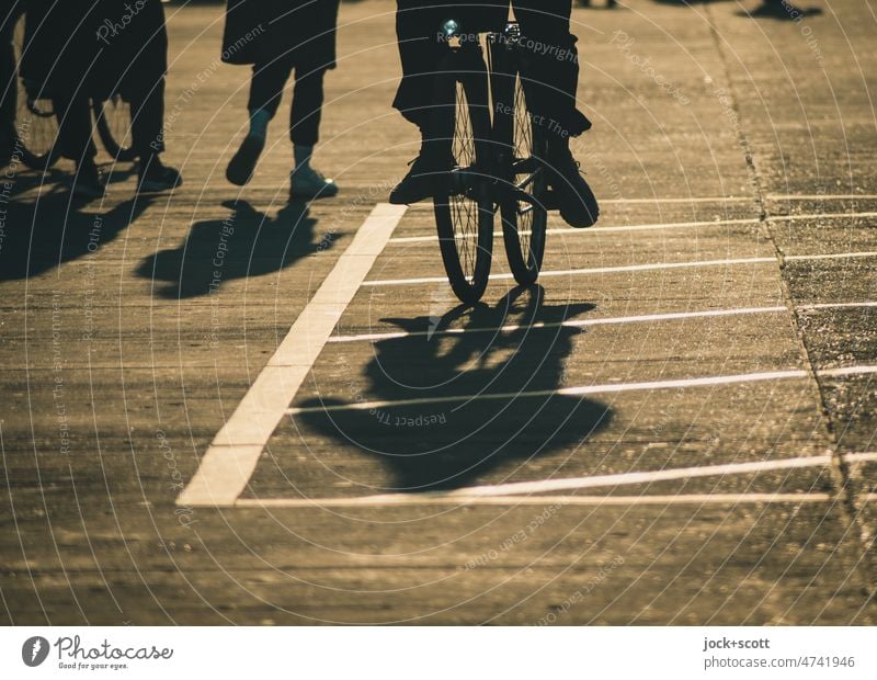 Silhouette von Menschen, fahren ein Fahrrad oder schlendern bei Sonnenschein Schatten Sonnenlicht Hintergrund neutral Frau Mann Wege & Pfade Schattenspiel