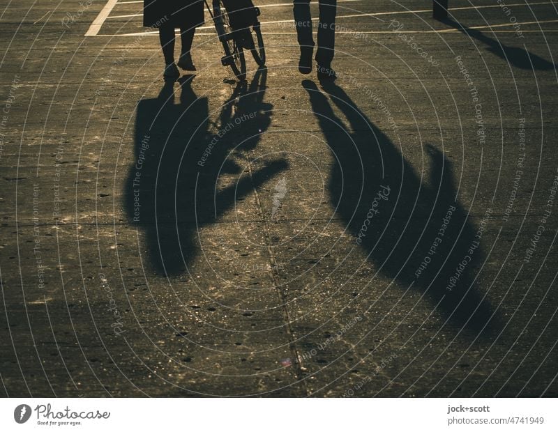 Silhouette von Menschen, die zusammen gehen und ein Fahrrad schieben bei Sonnenschein Schatten Sonnenlicht Hintergrund neutral Frau Mann Wege & Pfade