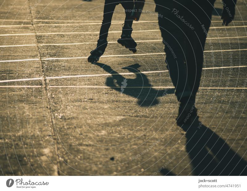 Silhouette von Menschen, fahren mit Rollerblades oder gehen im Sonnenschein Schatten Sonnenlicht Hintergrund neutral Wege & Pfade Schattenspiel Gegenlicht