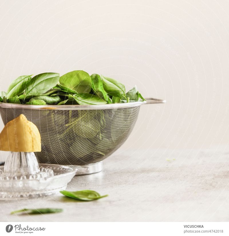 Lebensmittel Hintergrund mit Spinat Blätter in Sieb, Zitrone und Zitruspresse auf Küchentisch Lebensmittelhintergrund Wandhintergrund Gesundheit nahrhaft