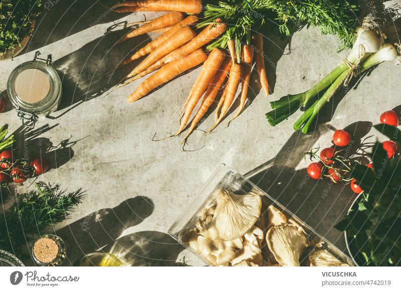 Verschiedene rohe Gemüse auf grauem Beton Küchentisch mit natürlichem Sonnenlicht verschiedene Essen zubereiten Vorbereitung Karotten Frühlingszwiebel