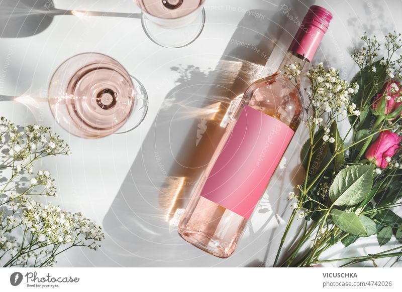 Rose Weinflasche mit leeren rosa mock up Etikett, Weingläser und Blumenstrauß Sonnenlicht Rosenwein Attrappe kennzeichnen zwei romantisch weißer Hintergrund