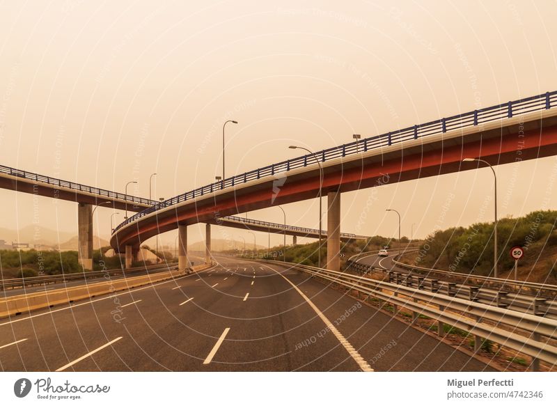 Autobahn mit Brücken in verschiedenen Höhen an einem Tag mit Saharastaub in der Umgebung, der eine neblige Atmosphäre schafft. Dunst Straße reisen Viadukt
