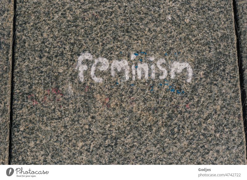'feminism' Wort auf Pflasterstein, Feminismus Frau Emanzipation Junge Frau Körper Gleichstellung Haut natürlich Schriftzeichen Demonstration
