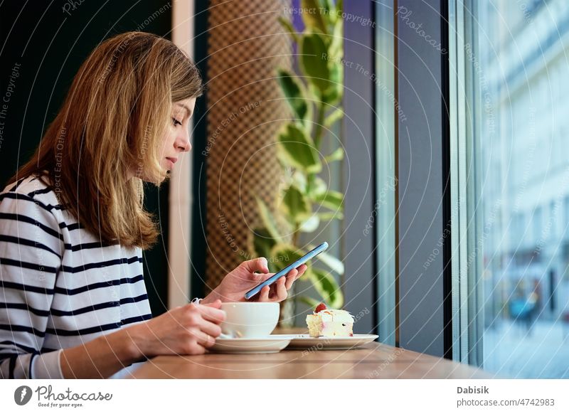 Frau frühstückt im Café, benutzt Smartphone im Café Kaffee Mitteilung verwenden online Nachricht digital freiberuflich Mobile Kaffeepause Telefon Medien Kuchen