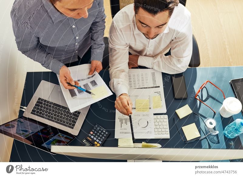 Geschäftskollegen besprechen Finanzdaten und arbeiten zusammen im Büro. Unternehmer arbeiten mit Diagrammen und Tabellen am Computer. Zwei Menschen arbeiten zusammen