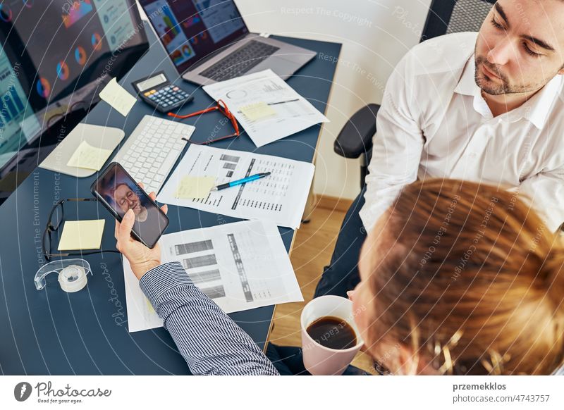 Geschäftskollegen, die per Videoanruf Finanzdaten besprechen und zusammen im Büro arbeiten. Unternehmer arbeiten mit Diagrammen und Tabellen am Computer. Team arbeitet zusammen