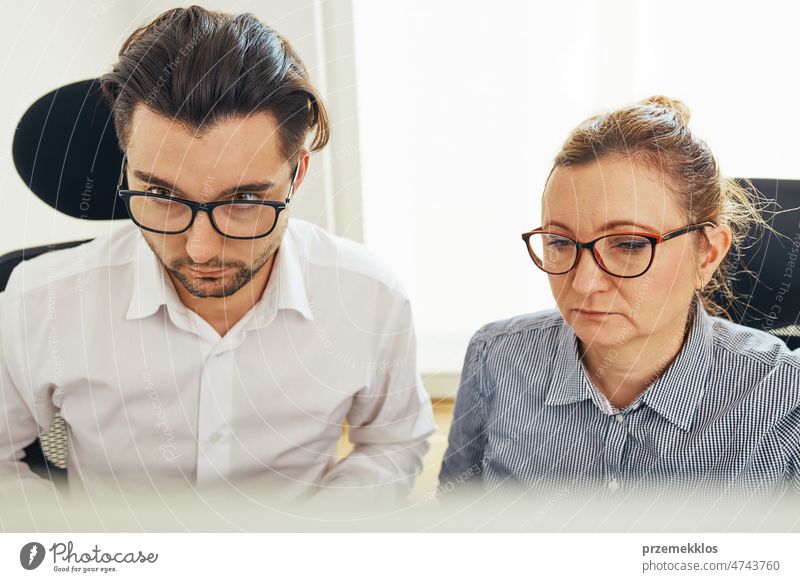 Zwei Geschäftsleute besprechen Finanzdaten und schauen auf den Computerbildschirm. Unternehmer arbeiten hart an Computer-Bildschirm im Büro sitzen. Menschen mit Frist arbeiten zusammen