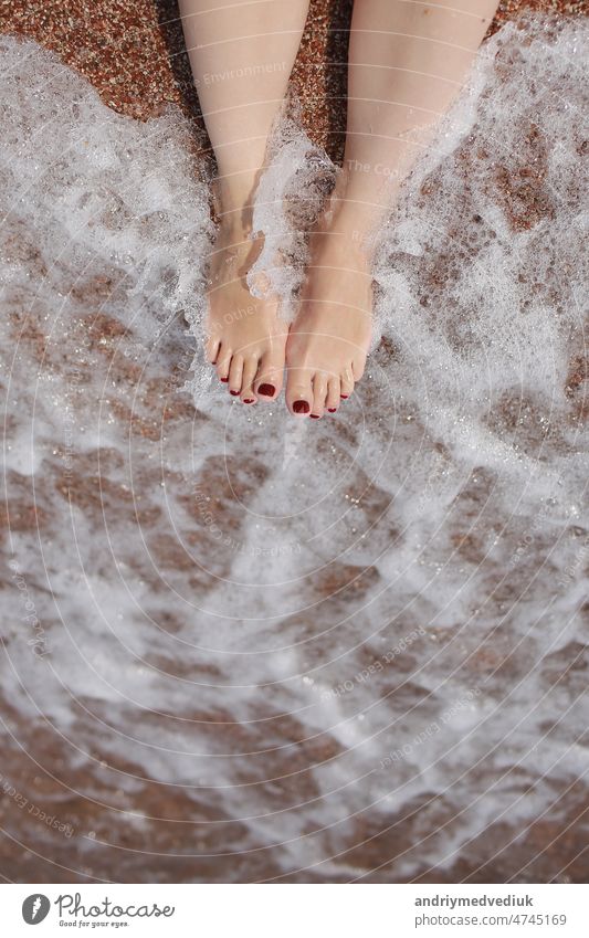 Reise-Konzept - Frau die Beine auf schönen tropischen Strand mit Kieselstein Sand. Füße auf Sand und Welle im Sommer. Mädchen barfuß im Ozean Wasser im Urlaub reisen. Fühlen Sie sich glücklich und entspannen. kopieren Raum.