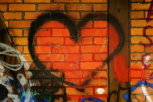 rotes Graffiti - Herz an einer Ziegelmauer / Liebeserklärung Ziegelwand sprayen Liebesbezeugung Liebelei Ziegelsteine Mauer Schmiererei Farbe Romantik