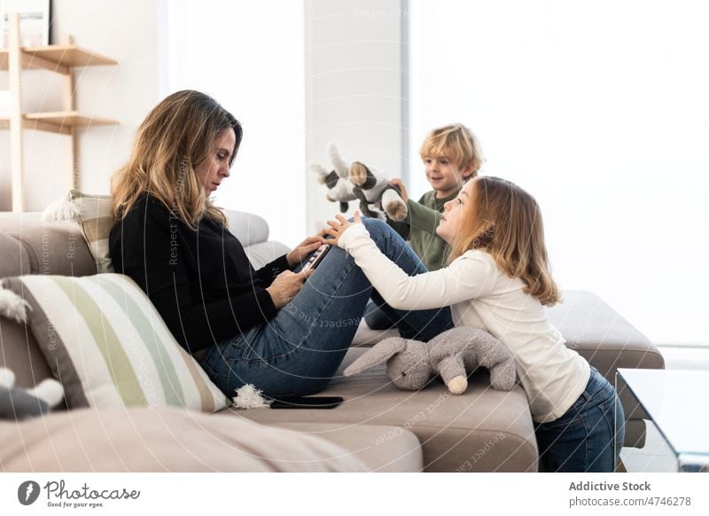 Kinder in der Nähe der Mutter, die auf der Couch ein Tablet benutzt Wohnzimmer Tablette Abhängigkeit Browsen online süchtig machend absorbieren ignorieren